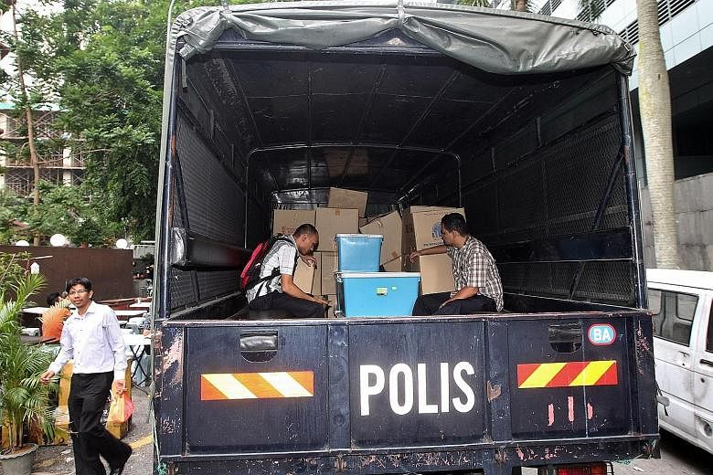 Officers from the special task force with boxes and computer hardware taken from 1MDB's headquarters last Wednesday. Part of its work is to look into the bank accounts of Prime Minister Najib Razak.