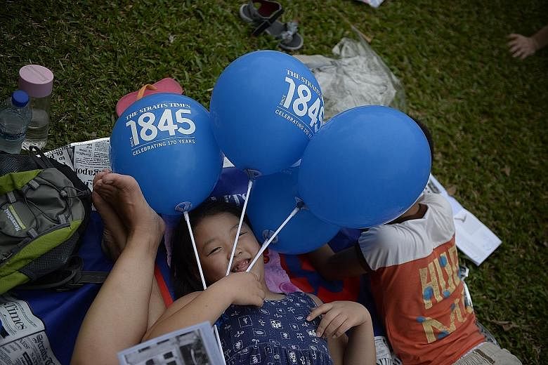 Commemorative gifts, such as ST170 picnic mats (above) and balloons, such as those held by six-year-old Nina Miao (left), were given out in the evening to the audience, who enjoyed a fine performance by the Singapore Symphony Orchestra (below), which