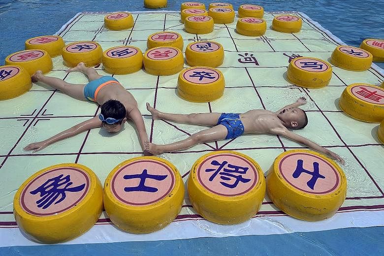 Children getting some respite from the intense heat atop a 20 sq m pool lounger shaped like a giant Chinese chessboard, at a water park in Chongqing.
