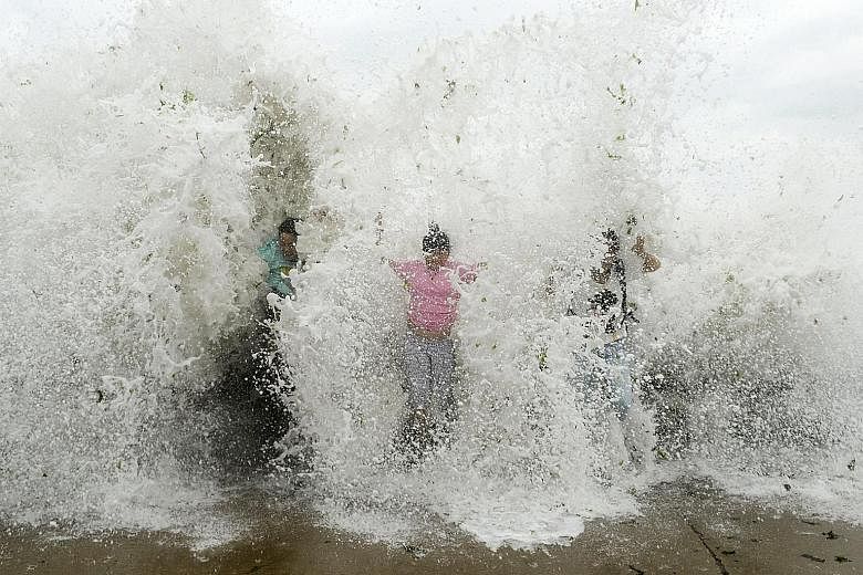 Tourists letting a surging wave hit them in Qingdao, Shandong province, yesterday. More than a million people in China were evacuated as Typhoon Chan-hom struck the eastern coast.