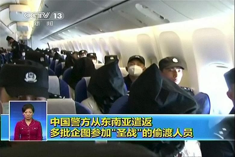 People being deported from Thailand seated in an airplane while flanked by police at an unidentified location in China.