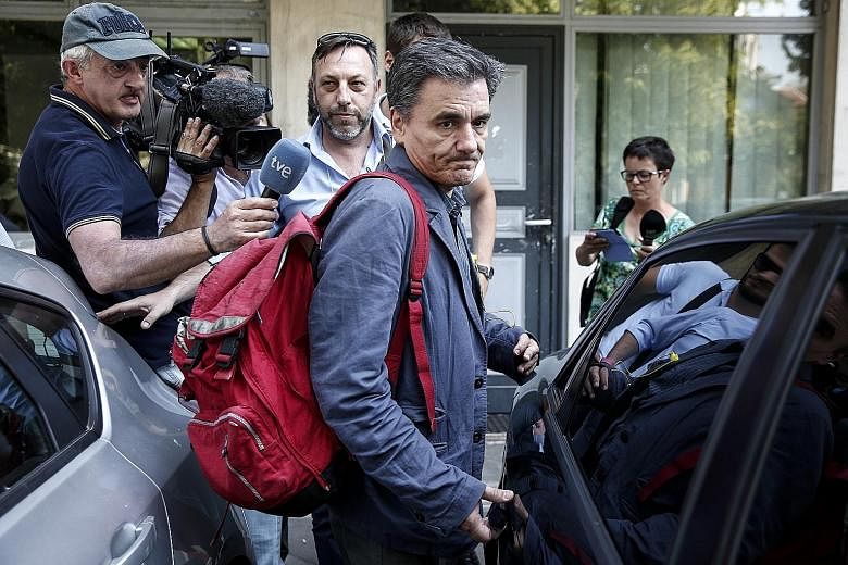 Greek Finance Minister Euclid Tsakalotos leaving after a meeting at the Syriza party headquarters in Athens yesterday. The ruling party and its junior coalition ally held meetings to prepare for Parliament sittings to pass laws which include plans fo