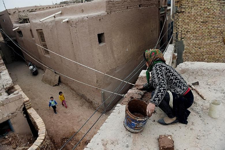 A woman repairing a roof in Kashgar in China's western Xinjiang province in April. With the increase in violence in the region, the authorities have banned veils, burqas and other Islamic forms of dress.