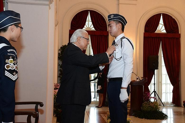 President Tony Tan conferring on Mr Evan Tan Jun Wen the President's Award at the Istana yesterday.