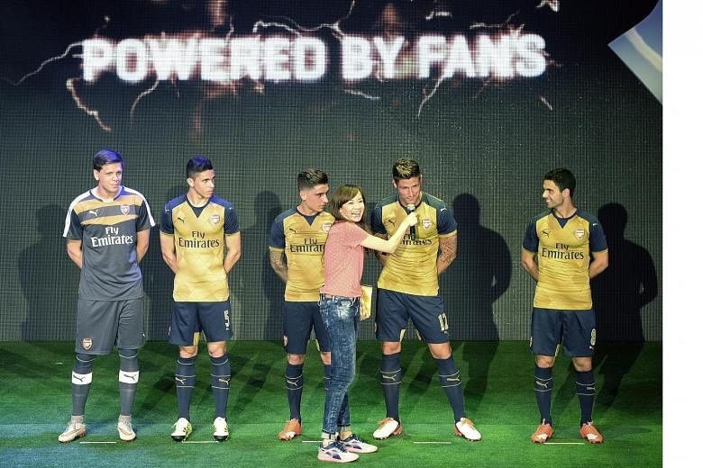Event host Jade Seah interviewing Arsenal striker Olivier Giroud - along with his Gunners team-mates (from left) Wojciech Szczesny, Gabriel Paulista, Hector Bellerin and Mikel Arteta - at the launch of the club's new away kit at the Esplanade Outdoor
