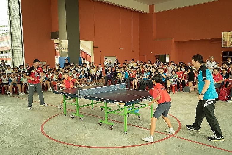 Gao Ning (left, in red jersey) and Li Hu (in blue), men's doubles champions at last month's SEA Games, were among the national table tennis players who spent time at Qi Hua Primary School yesterday. They sparred with pupils and taught them the import