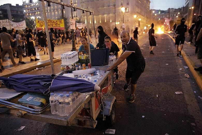 Food vendors fleeing Syntagma Square in Athens on Wednesday during police clashes with protesters angry at the austerity measures that were passed by the Greek Parliament in return for talks on a new aid package from the euro zone.