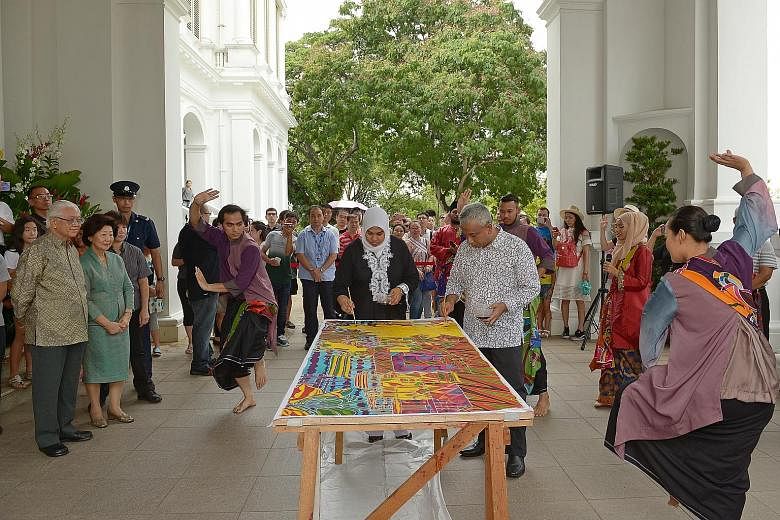 Artist Ika Zahri Sarkasi and his wife, Madam Zarinah Begum, painting a batik piece in the presence of President Tony Tan Keng Yam and his wife Mary at the Istana Open House yesterday in celebration of Hari Raya Puasa. The artists were joined by Malay
