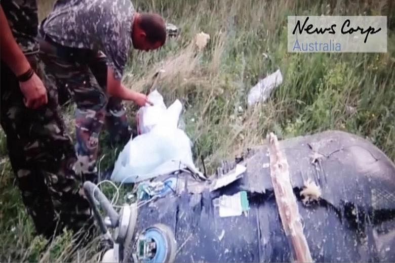 This screen grab, taken from a video released by News Corp Australia yesterday, allegedly shows Russian-backed rebels looking at what is apparently one of the "black boxes" of the Malaysia Airlines plane shortly after it crashed near the village of G