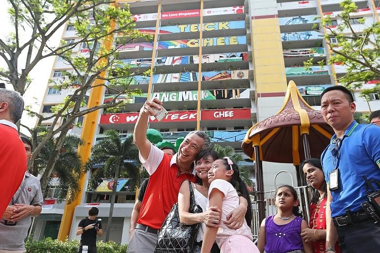 PM Lee Hsien Loong taking a wefie with residents in his Teck Ghee ward. He added the finishing touches to a canvas painting used to complete an art facade (background) on one of the HDB blocks.