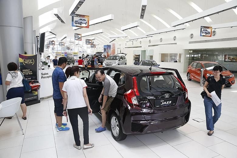 Customers at the Honda showroom in Alexandra Road yesterday. Some showrooms reported an increase in the number of walk-in customers. Prices of new cars have fallen as COE prices drop to their lowest in at least five months in the latest COE tender on