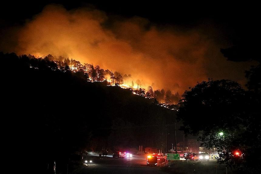 Los Angeles county firefighters battling a brush fire in Wrightwood, California, on Friday. The flames spilled onto a busy highway linking Los Angeles and Las Vegas, destroying several dozen cars and trucks abandoned by their fleeing owners. Televisi