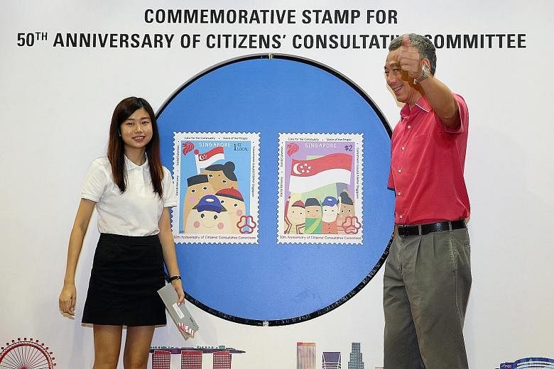 Prime Minister Lee Hsien Loong unveiling stamp designs commemorating the 50th Anniversary of the Citizens Consultative Committee yesterday. Ms Mavis Tan (left) from ITE College Central beat more than 90 other entries in a stamp design competition org
