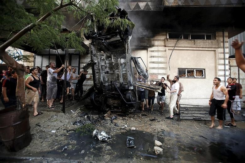 Palestinians inspecting a car after it was blown up in Gaza City yesterday. The early morning explosions destroyed five cars belonging to members of the Al-Qassam and Al-Quds brigades, and seemed to be a warning rather than an attempt to inflict casu