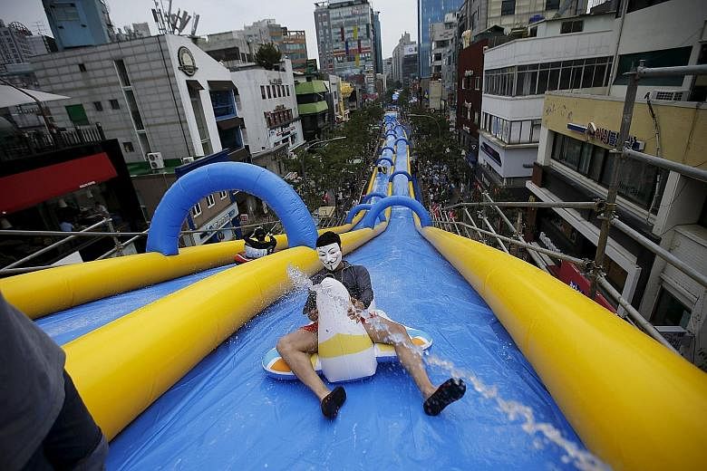 A man wearing a Guy Fawkes mask enjoying a ride on a 350m-long water slide during the City Slide Festa in Seoul yesterday. The water slide in the South Korean capital is the longest recorded in the country, local media said. And a local official said