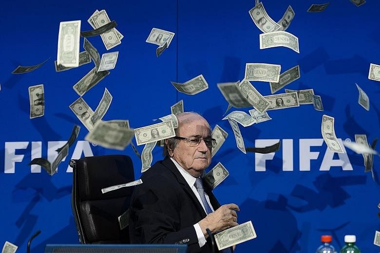A clearly unimpressed Fifa president Sepp Blatter looking at fake dollar bills flying around him during a press conference at the football world body's headquarters in Zurich. The notes were thrown by a protester.
