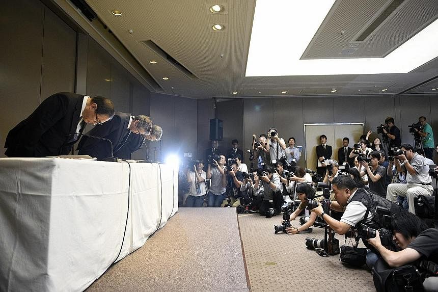 Toshiba president Hisao Tanaka (centre), chairman Masashi Muromachi (left) and executive officer Keizo Maeda bowing during a press conference yesterday at the company's headquarters in Tokyo. Three executives resigned to take responsibility for a US$