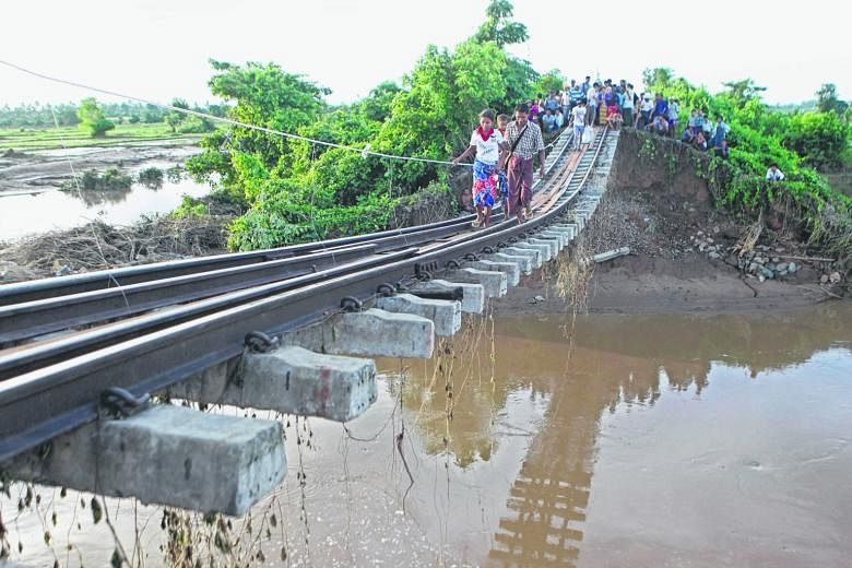 People making their way along a broken, flood- damaged bridge in Kanbalu, Sagaing division, Myanmar, on Tuesday. Monsoon rains have led to floods across the country. Several people have died and thousands are fleeing their homes.