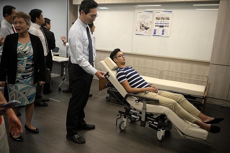 Left: President Tony Tan Keng Yam checking out Nico, a robot that can extract data such as blood pressure or temperature from wearable devices on patients and send the data to a doctor's computer. Nico can also be used in the wards to keep an eye on 