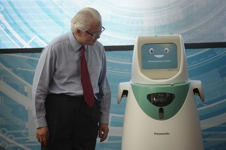 Left: President Tony Tan Keng Yam checking out Nico, a robot that can extract data such as blood pressure or temperature from wearable devices on patients and send the data to a doctor's computer. Nico can also be used in the wards to keep an eye on 
