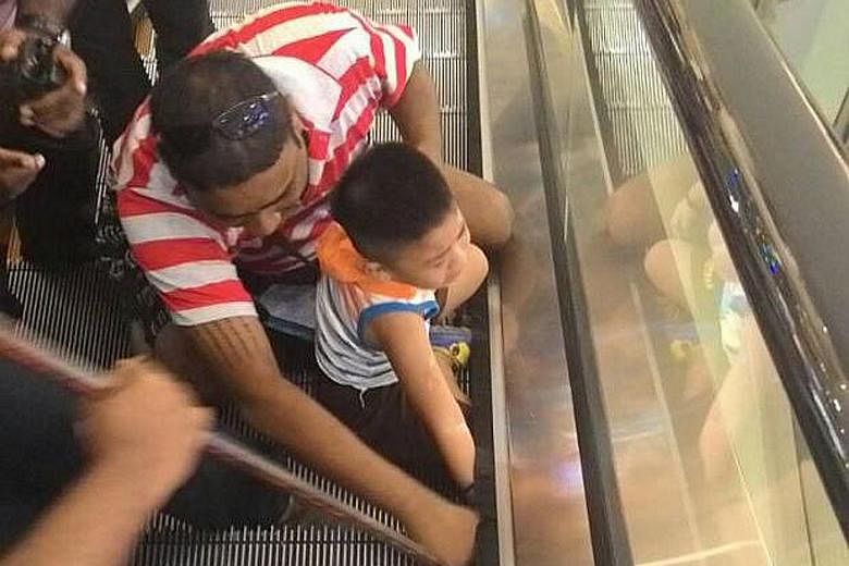 Mr Ng Wei Kang trying to free his son's hand which was stuck in the escalator. The skin on the boy's hand was torn off, but no bones were broken.