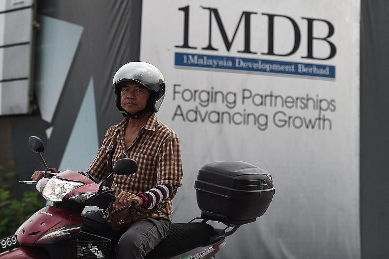 A motorcyclist rides past hoarding at the construction site of 1MDB's flagship Tun Razak Exchange in Kuala Lumpur.