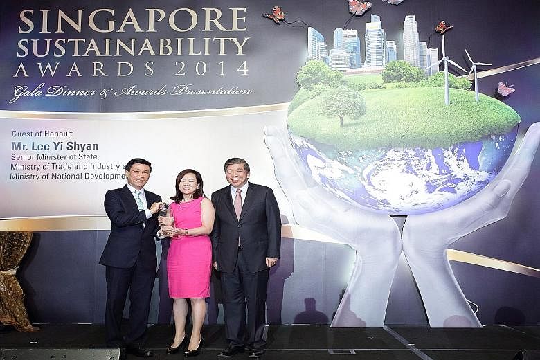 Ms Esther An receiving CDL's Sustainable Business Award 2014 in the category for large companies, flanked by Mr Lee Yi Shyan (left), Senior Minister of State for Trade and Industry and National Development, and Mr Teo Siong Seng, Singapore Business F