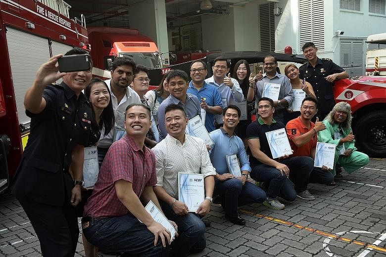 Lieutenant- Colonel Eric Chua, head of operations at the 1st SCDF Division, taking a wefie with the 16 men and women who received awards for their public spiritedness yesterday, as well as 1st SCDF Division commander Alan Chow (right). The award recip