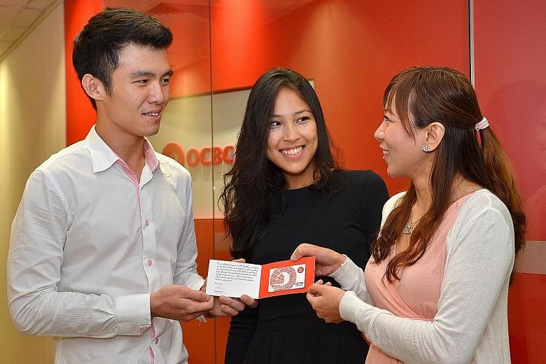 OCBC personnel (from far left) Mr Ben Chua, Ms Aisha Lin and Ms Jessica Huang with the exclusive SG50 Nets Flashpay card that all local staff will get, among other SG50 rewards. The bank will also set aside about $500,000 for its overseas staff to ho