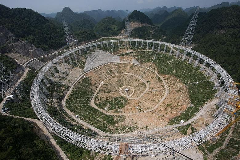 China is building the world's biggest radio telescope. Seen here under construction in Guizhou, the 500m-aperture spherical telescope's enormous dish is larger than 30 football fields, and will be connected to one of the world's fastest computers to 