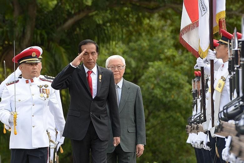 Indonesian President Joko Widodo saluting as he inspected an honour guard with President Tony Tan Keng Yam during a welcome ceremony at the Istana yesterday. Mr Joko urged investors to look to Indonesia, where he says "a new economic cycle is beginni