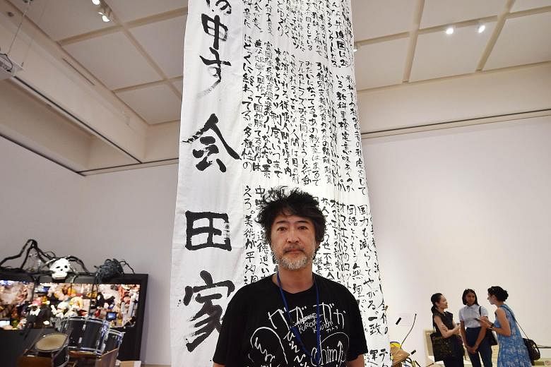 Artist Makoto Aida with his calligraphy work that mildly mocks Japan's education ministry.
