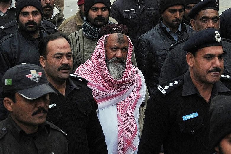 Malik Ishaq, head of the Lashkar-e- Jhangvi, being escorted to court in Lahore last December. Ishaq had faced several murder trials but had always been acquitted after witnesses refused to testify.