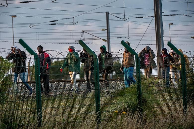 Illegal migrants who successfully got into the Eurotunnel terminal in France on Tuesday walking along a railroad track as they try to reach a shuttle to Britain. An official count early this month showed about 3,000 migrants - mainly from Ethiopia, E