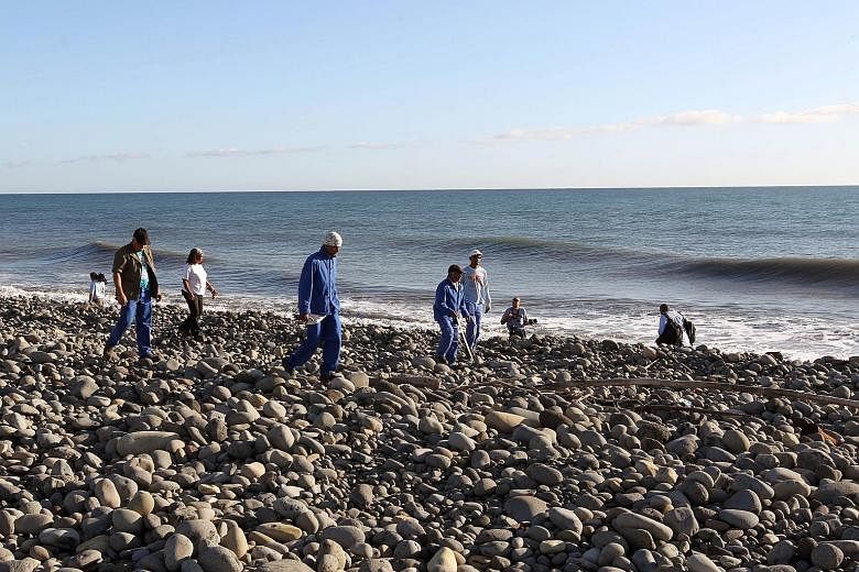 Volunteers in charge of coastal cleaning searching for more aircraft debris yesterday after finding part of a plane wing and a piece of torn luggage on Wednesday on the Saint-Andre shore on Reunion Island.