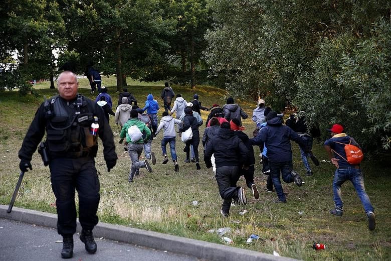 Migrants from the makeshift refugee camp in Calais, France, trying to escape from the French police on Thursday as they attempt to catch a train to reach Britain via the Channel Tunnel.