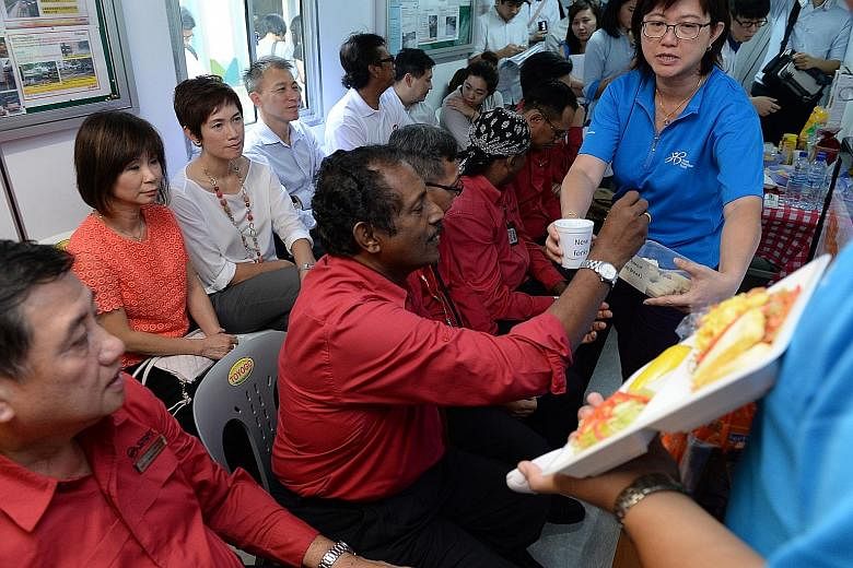 Bus captains trying out healthier food options recommended by the Health Promotion Board, at the SMRT Choa Chu Kang bus interchange, as Senior Minister of State for Health and Manpower Amy Khor (back row, in red) and Senior Minister of State for Fina