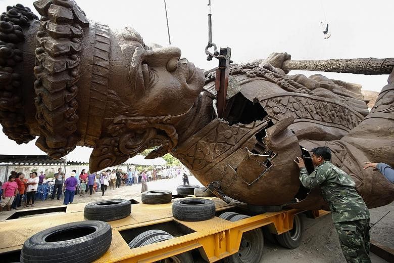 Meanwhile, a Thai soldier inspects damage to a statue of King Narai the Great, caused during its transportation to the park in Hua Hin.