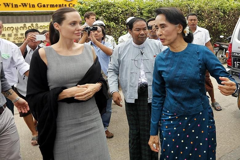 American actress Angelina Jolie (left) and Myanmar's opposition leader Aung San Suu Kyi (in blue) arriving at a slum area in the Hlaing Thar Yar township in Yangon yesterday. The Oscar-winning star, who is on a six-day visit to Myanmar as the goodwil