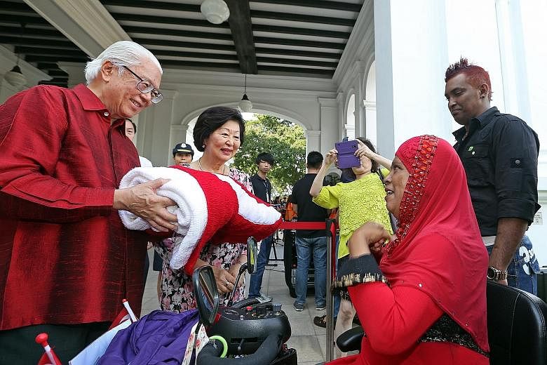 Ms Bashiran Bibi, 59, and her son Abdul Rahim, 36 (right), presenting a 1.3m by 1.8m national flag which she hand-knitted to President Tony Tan Keng Yam and his wife, Mary, at the Istana Open House yesterday. They were among more than 16,000 visitors
