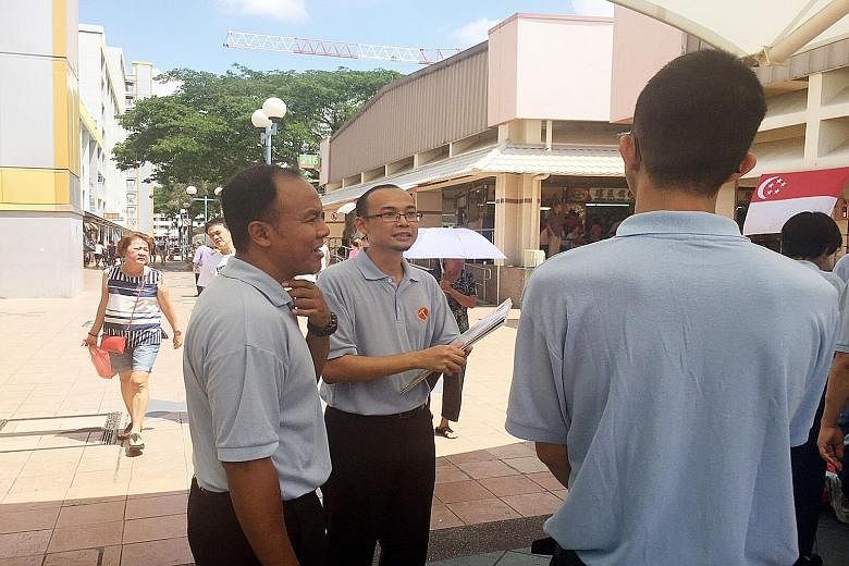WP member Mohamed Fairoz Shariff (centre, with Aljunied GRC MP Faisal Abdul Manap) at the Fengshan Block 85 Market and Food Centre yesterday.