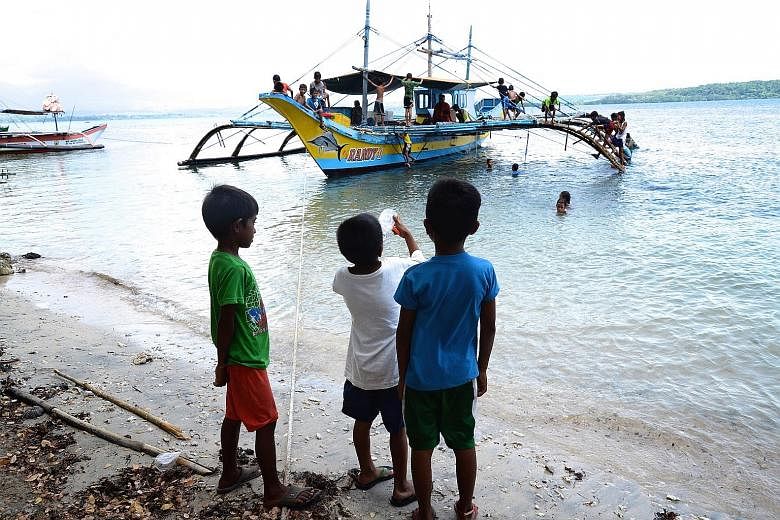Above: Children playing on the last fishing boat in Masinloc to have sailed to Scarborough Shoal. Right: Herrings salted and laid out to dry in Masinloc, whose dwindling number of fishermen now do not venture beyond the local bay. Clockwise from abov