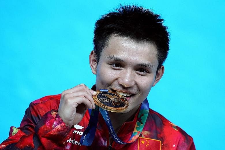 Qiu Bo of China bites his gold medal after winning the men's 10m platform final.