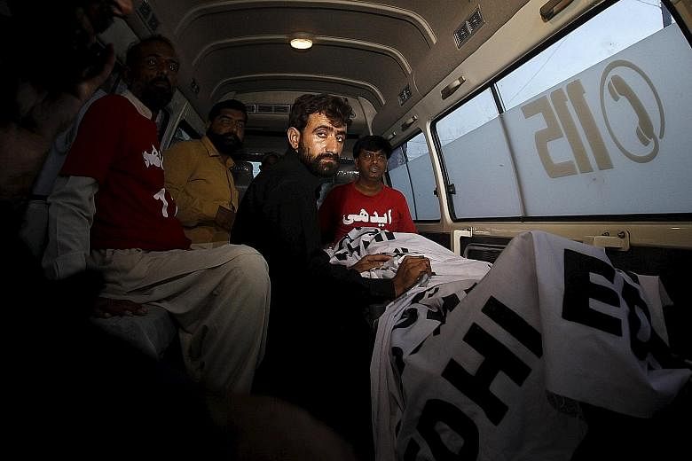 Mr Abdul Majeed, brother of Shafqat Hussain (right) who was convicted of killing a child in 2004, sitting in an ambulance beside Hussain's body after his execution in Karachi yesterday. Hussain's family and lawyers say that he had been under 18 at th