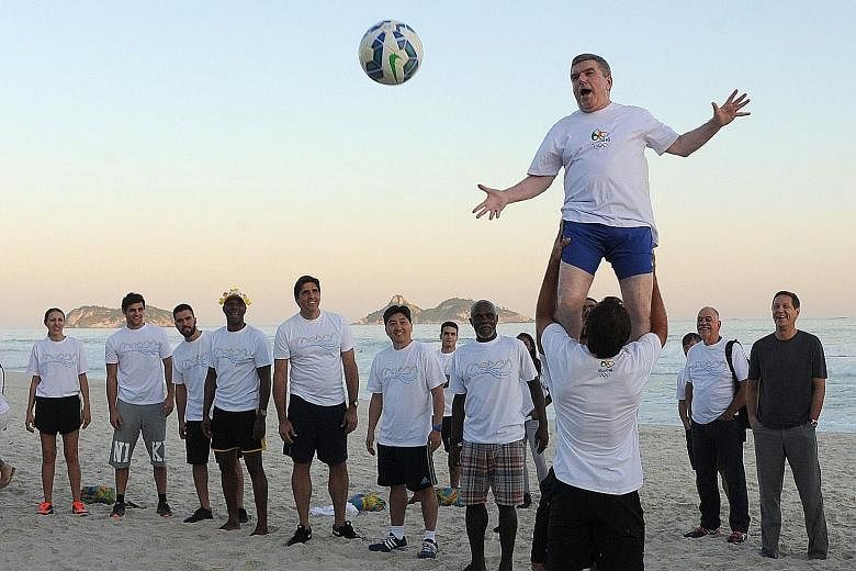 International Olympic Committee president Thomas Bach (top) takes part in an event at Barra da Tijuca Beach in Rio de Janeiro on Tuesday, one year before the start of the 2016 Olympic Games.