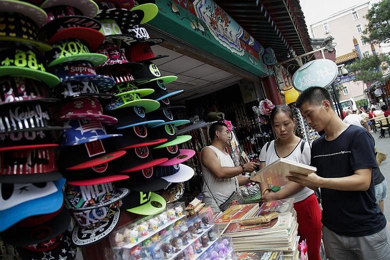 Customers at a shopping district in Beijing. China's economic slowdown is one of the factors contributing to the hammering of the 30 blue chips that make up the Straits Times Index. The stocks have dropped 7.6 per cent in the past 12 months.