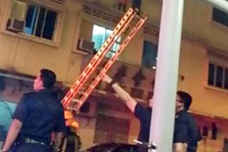 Two foreign workers awaiting rescue on the ledge outside the window of a house in Lorong 4 Geylang last December as a fire raged within. Four Malaysian cleaners died in the blaze.