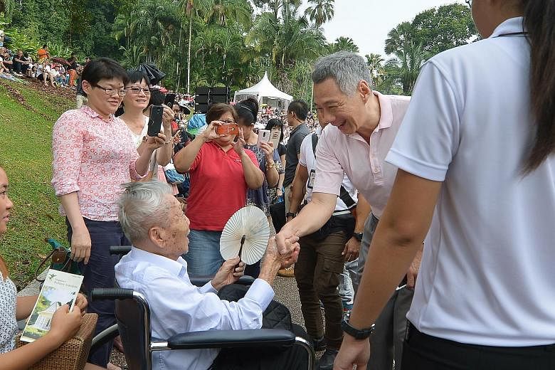 Prime Minister Lee Hsien Loong chatting with 101-year-old Mr Heng Kok Kai, a retired photographer, as Mr Heng's daughter Betty (in red top) snapped a photo of them, at the Botanic Gardens yesterday. Mr Heng, who enjoys music and being out among the l