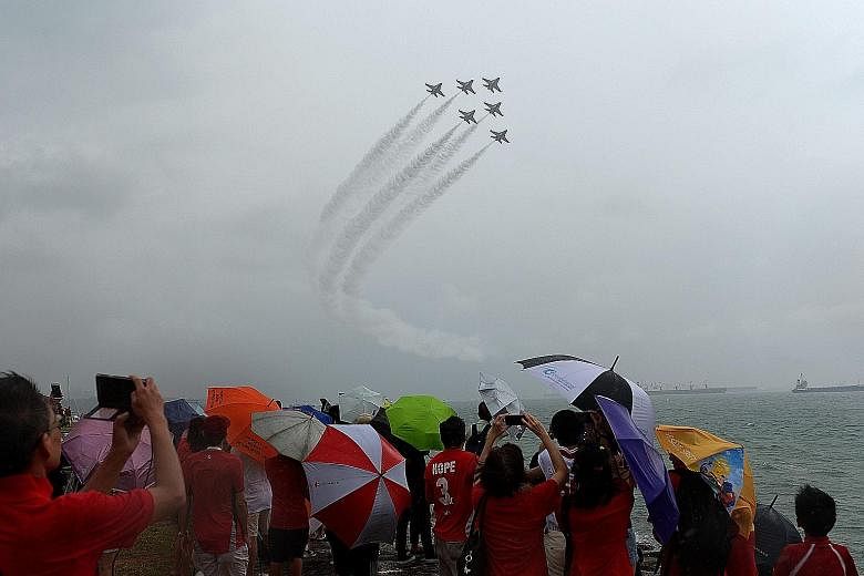 Families gathering along the coastline of Marina South to catch the Black Knights aerial display. The show was one of the events held yesterday to mark the nation's 50th birthday.