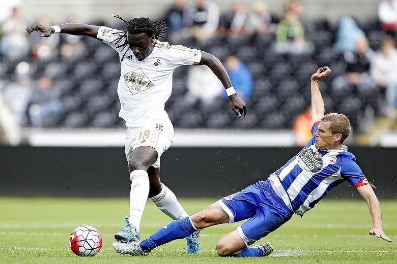 Bafetimbi Gomis (left), Swansea City's top scorer last season with 10 goals, in action against Alex Bergantinos of Deportivo La Coruna in a pre-season friendly. Swansea finished eighth in the EPL last term but will have their work cut out at Stamford